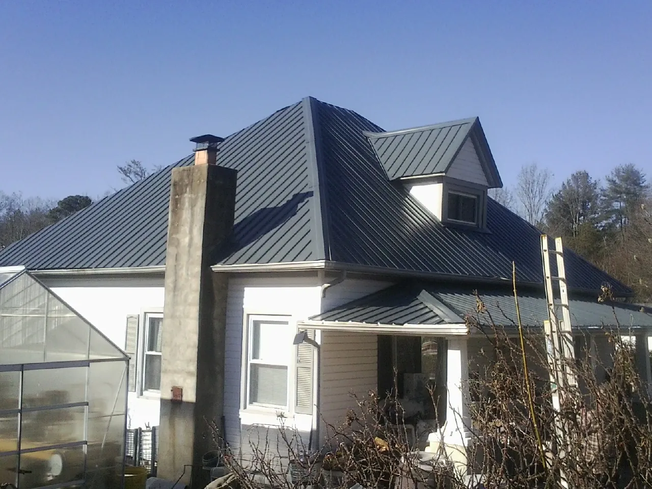 Dark blue standing seam metal roof on a white farmhouse with dormer — Slate & Tile Roof Repair by Roofing Brothers in Velpen
