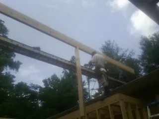 Carpenter setting a ridge beam over a new addition frame — Ice Dam Removal by Roofing Brothers in Velpen