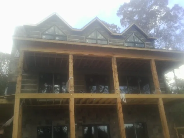 Dormers and porch framing on a large log home under construction — Roof Coating work by our crew in Velpen