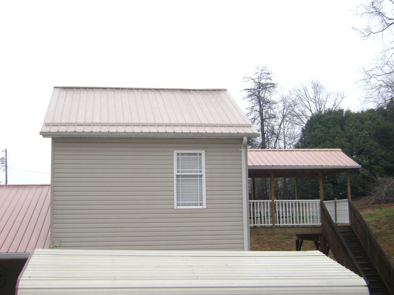 Tan metal roofs on a two story addition and attached porch in Velpen