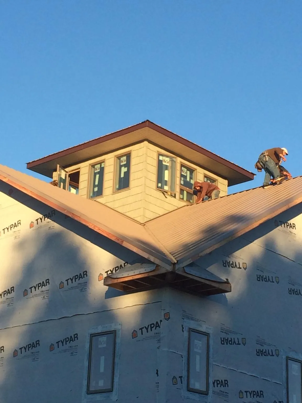 Roofers working around a rooftop cupola on a new metal roof at sunset — Roof Waterproofing in Velpen by Roofing Brothers